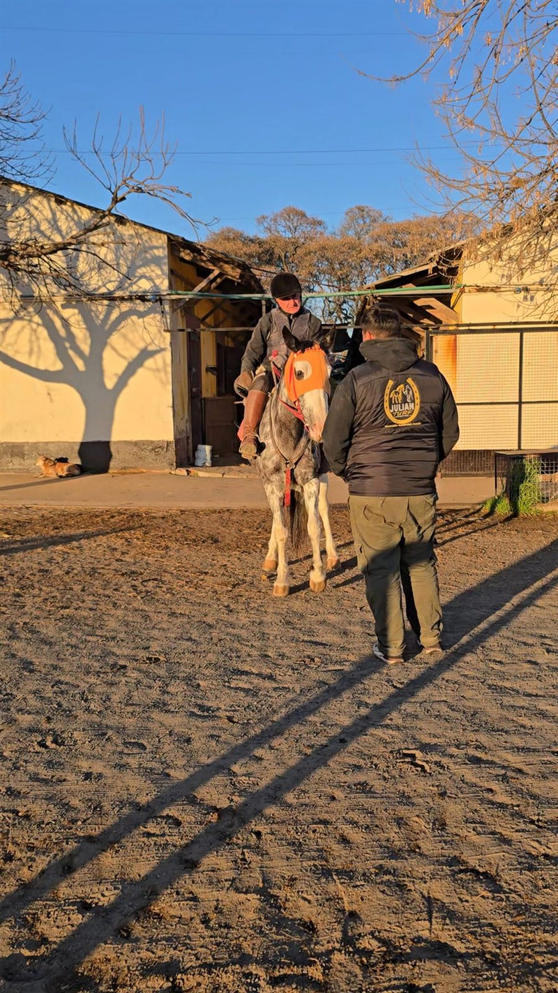Julián hablando con el jinete arriba de un tordillo en el stud antes de salir a entrenar